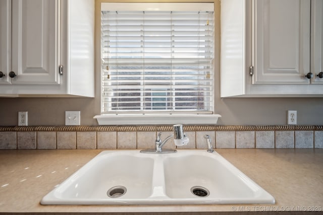 details with white cabinetry, light countertops, and a sink