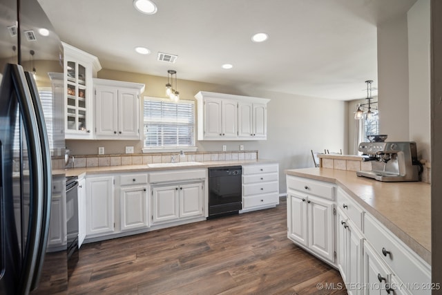 kitchen with visible vents, a sink, freestanding refrigerator, white cabinets, and dishwasher