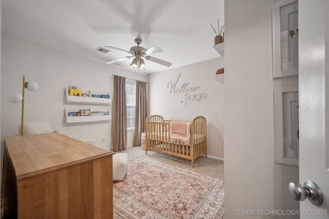 carpeted bedroom with a nursery area, baseboards, visible vents, and ceiling fan