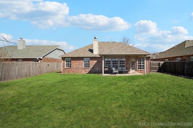 back of property with a patio, a fenced backyard, a yard, brick siding, and a chimney