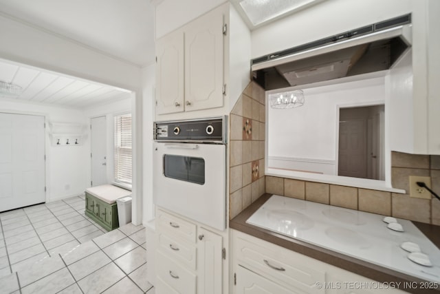 2503 S Pittsburg Ave, Tulsa, OK 74114 - kitchen featuring white oven, light tile patterned floors, white cabinets, a notable chandelier, and ventilation hood