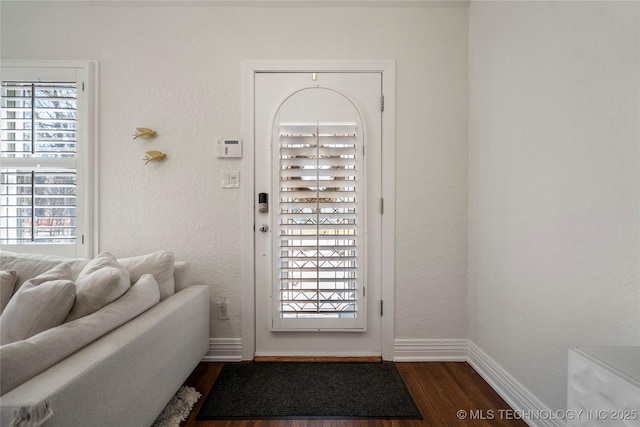 entryway with dark wood-type flooring, baseboards, and a textured wall