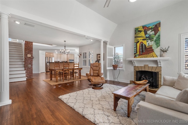 living room featuring baseboards, dark wood-style flooring, ornate columns, and a tile fireplace