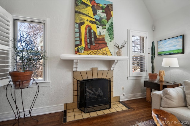 living area featuring vaulted ceiling, a healthy amount of sunlight, baseboards, and wood finished floors