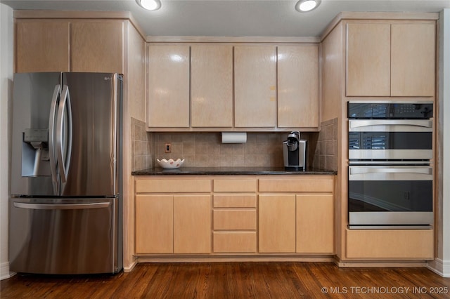 kitchen with backsplash, dark wood finished floors, recessed lighting, dark stone countertops, and stainless steel appliances