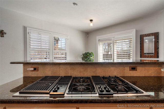 kitchen with a wealth of natural light, stovetop with downdraft, and dark stone countertops