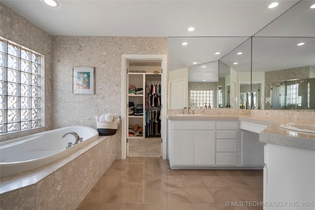 full bath featuring vanity, a shower stall, a bath, and a healthy amount of sunlight