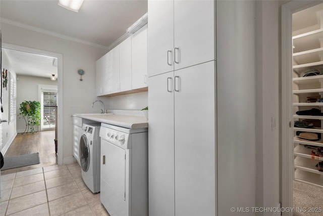 washroom featuring ornamental molding, light tile patterned floors, separate washer and dryer, cabinet space, and a sink