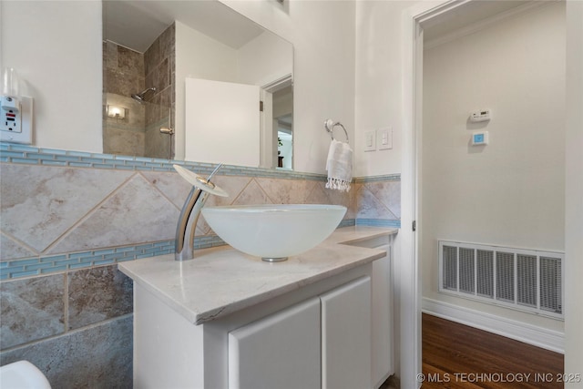 bathroom featuring visible vents, tile walls, vanity, and tiled shower