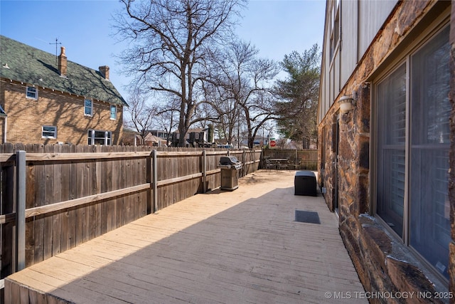 wooden terrace featuring area for grilling and a fenced backyard