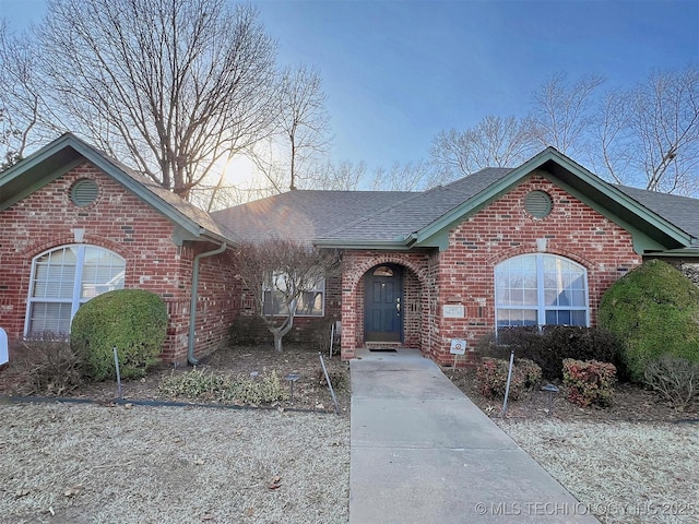 view of front of home with brick siding and a shingled roof