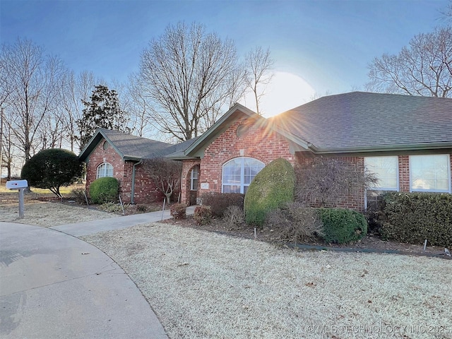 ranch-style house with brick siding, driveway, and a shingled roof