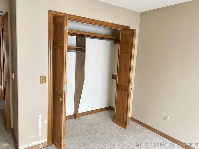 unfurnished bedroom with light carpet, a closet, and baseboards