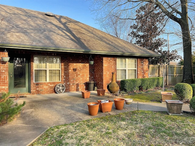 back of property featuring a patio, fence, a yard, a shingled roof, and brick siding