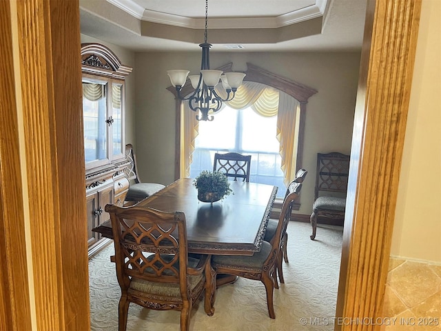 dining space featuring a raised ceiling, an inviting chandelier, and ornamental molding