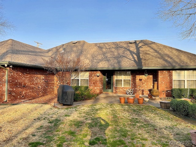 rear view of house featuring brick siding, a shingled roof, and a patio area