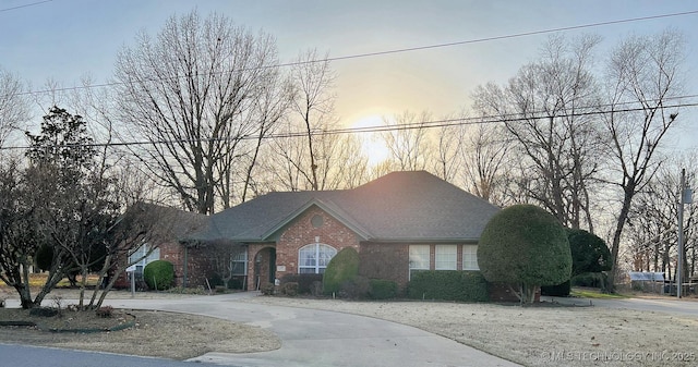 view of front of house featuring brick siding, concrete driveway, and a shingled roof