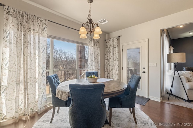 dining area featuring visible vents, wood finished floors, and a chandelier