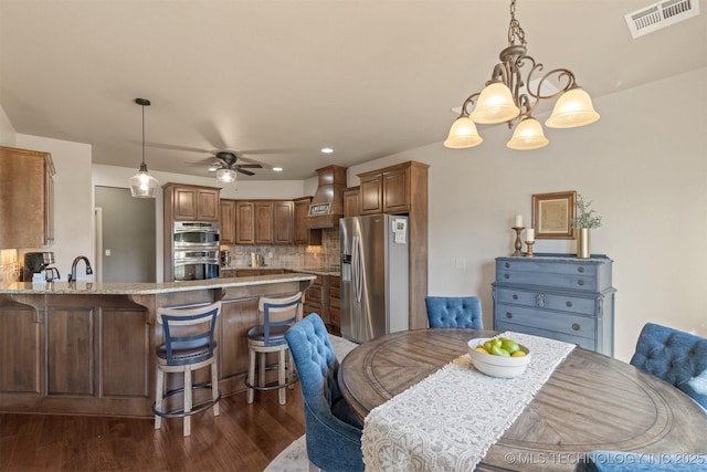 dining space featuring recessed lighting, visible vents, dark wood-style flooring, and ceiling fan with notable chandelier