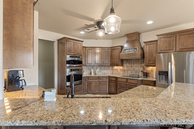 kitchen with backsplash, appliances with stainless steel finishes, custom range hood, and light stone countertops