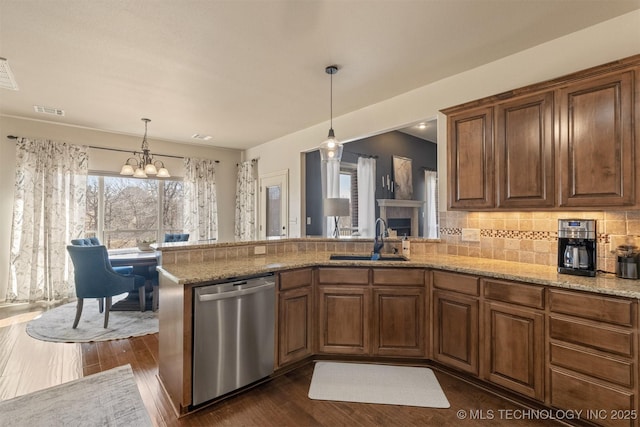 kitchen with light stone counters, dishwasher, a peninsula, and a sink