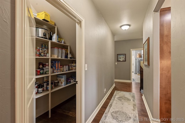 corridor with dark wood-type flooring and baseboards