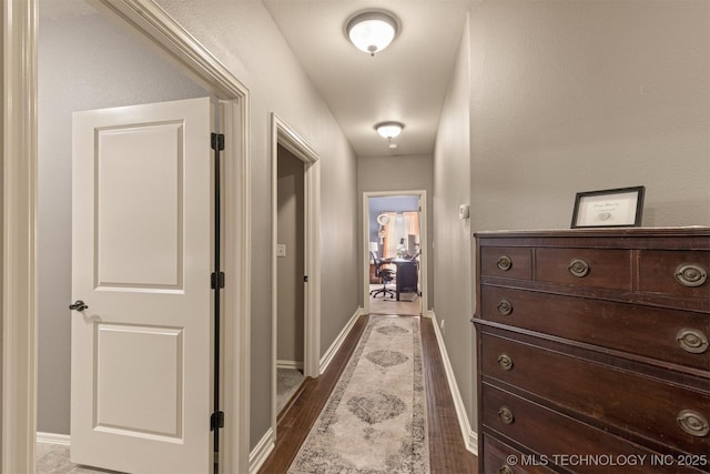 hallway featuring baseboards and dark wood-type flooring