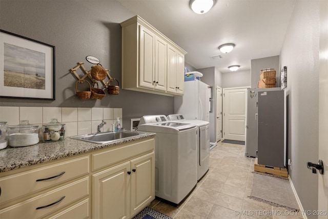 laundry area with light tile patterned floors, baseboards, cabinet space, a sink, and washer and dryer