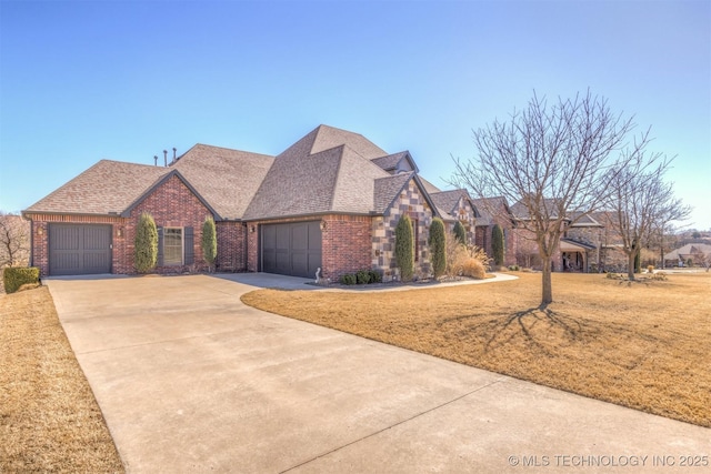 view of front of house with a front yard, driveway, a shingled roof, a garage, and brick siding