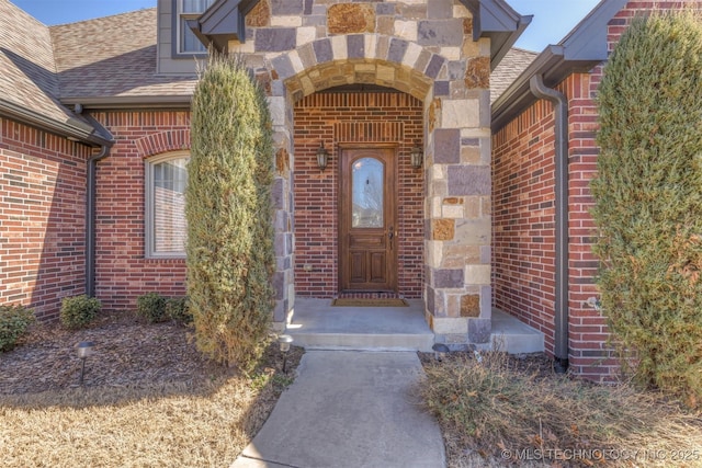 property entrance featuring brick siding, stone siding, and a shingled roof