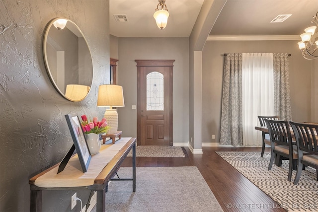 foyer entrance featuring wood finished floors, visible vents, a textured wall, and arched walkways