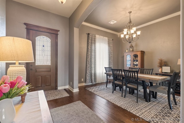 dining room with visible vents, baseboards, hardwood / wood-style floors, an inviting chandelier, and arched walkways