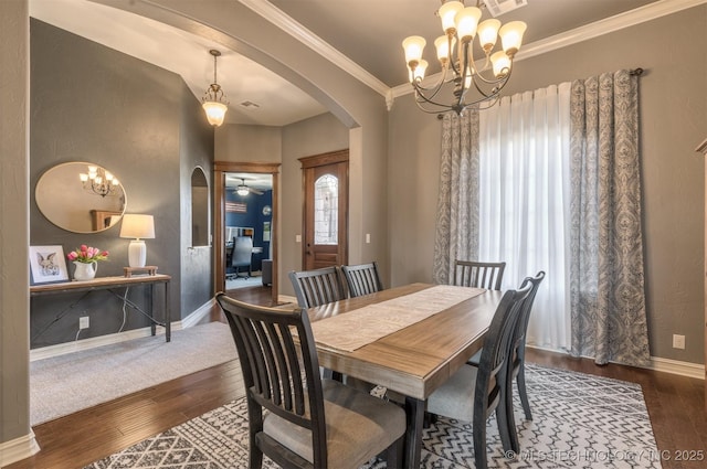 dining room with baseboards, arched walkways, wood finished floors, and crown molding