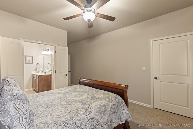 bedroom with light carpet, ensuite bathroom, a sink, baseboards, and ceiling fan