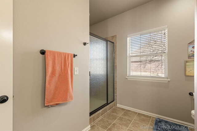 bathroom with tile patterned floors, toilet, baseboards, and a stall shower