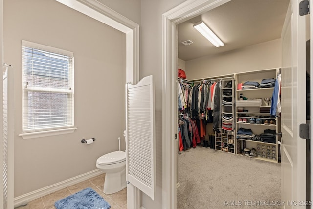 bathroom with tile patterned flooring, visible vents, a walk in closet, baseboards, and toilet