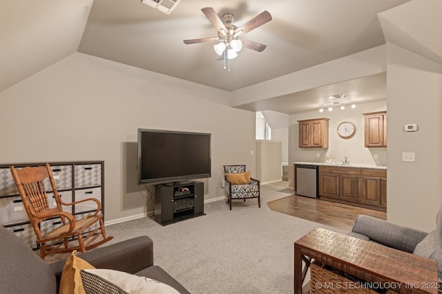 living room featuring visible vents, lofted ceiling, light carpet, wet bar, and a ceiling fan