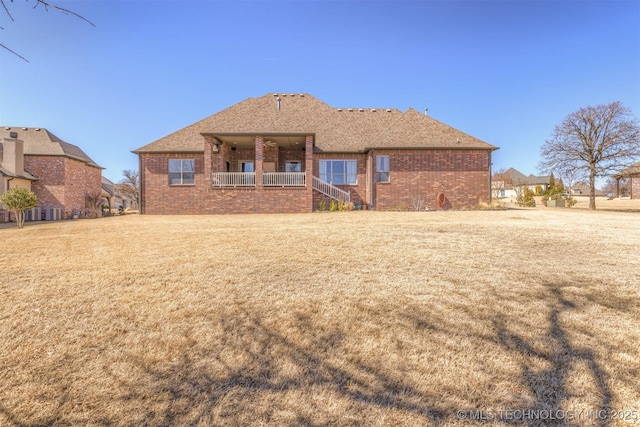 rear view of house with stairway, brick siding, and a lawn