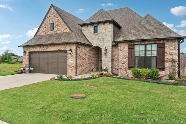 french country home with brick siding, stone siding, a shingled roof, and a front yard