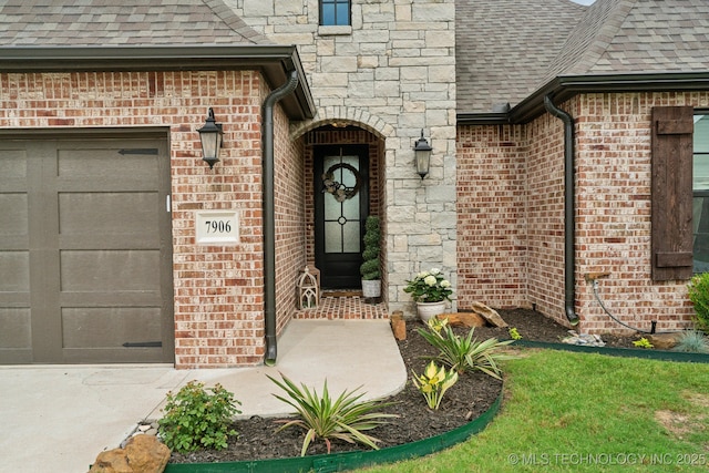 property entrance with stone siding, an attached garage, brick siding, and roof with shingles