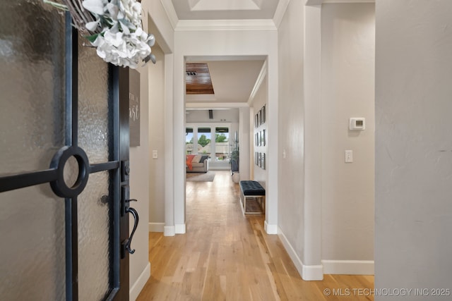 hall with baseboards, crown molding, and light wood-style floors