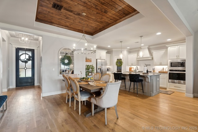 dining area featuring a tray ceiling, wood ceiling, a chandelier, and light wood-style flooring