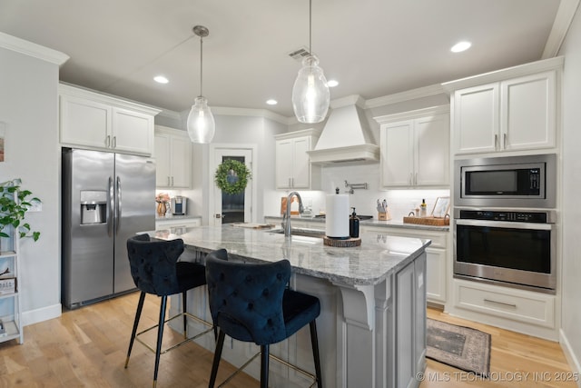 kitchen featuring premium range hood, visible vents, backsplash, appliances with stainless steel finishes, and white cabinets