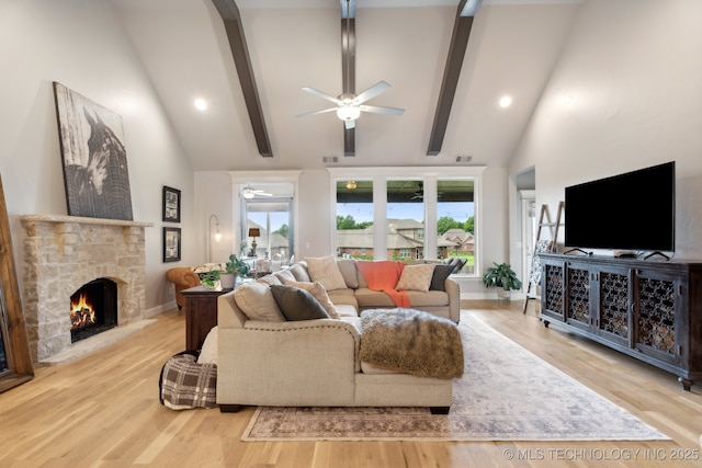 living room featuring beamed ceiling, a stone fireplace, wood finished floors, high vaulted ceiling, and a ceiling fan