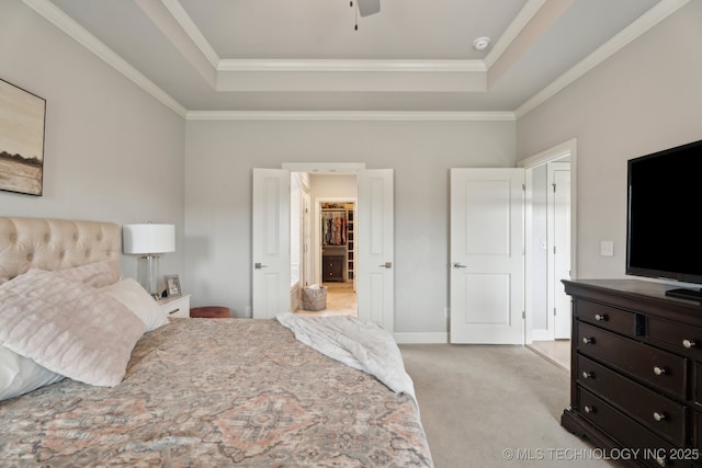 bedroom with a tray ceiling, light colored carpet, a spacious closet, and crown molding