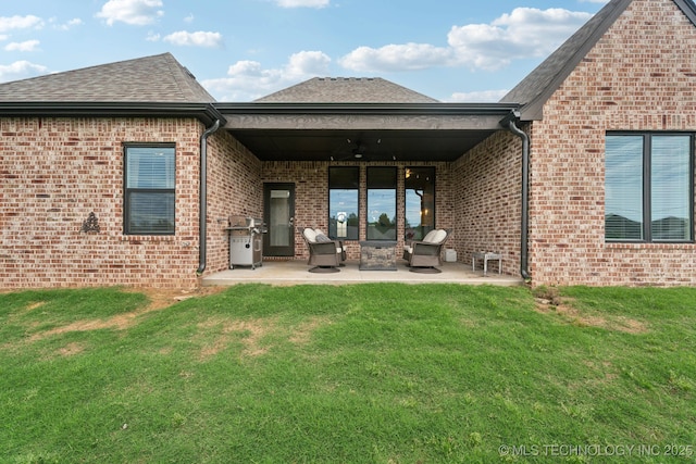 back of property with a patio area, a ceiling fan, a yard, and brick siding