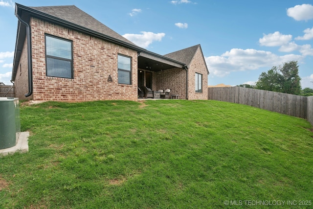 rear view of property with a patio, a lawn, a fenced backyard, and brick siding