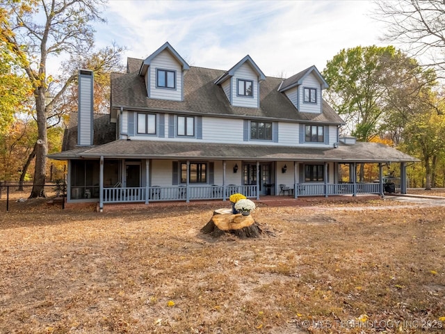 country-style home featuring a chimney, covered porch, and a shingled roof