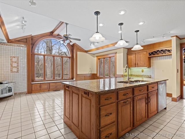 kitchen featuring brown cabinets, a sink, lofted ceiling with beams, stainless steel dishwasher, and a wood stove