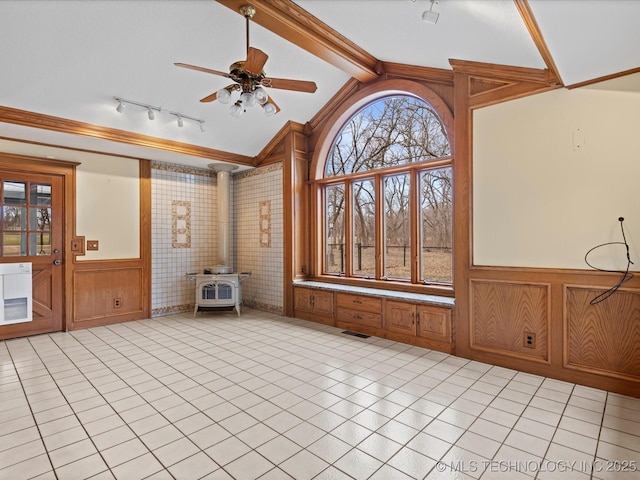 unfurnished sunroom featuring visible vents, track lighting, lofted ceiling with beams, ceiling fan, and a wood stove